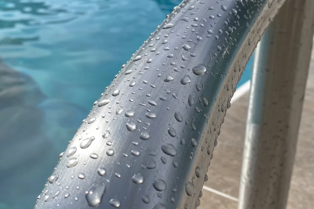 Nahaufnahme einer Edelstahloberfläche am Pool mit Wassertropfen