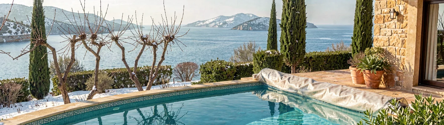 Pool eines Ferienhauses im Winter mit kahlen Weinreben, Zypressen und Blick auf das Meer