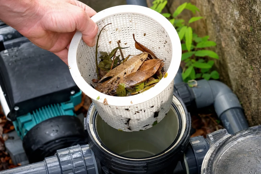 Geöffneter Vorfilterkorb einer Poolpumpe mit aufgefangenem Laub