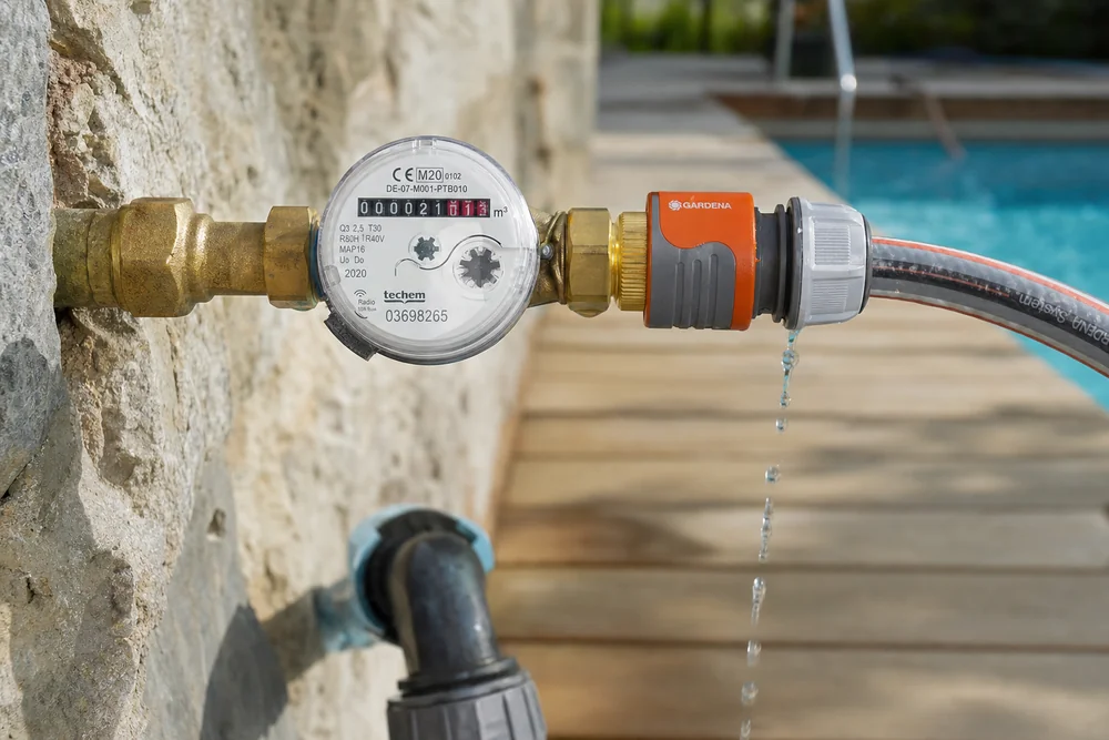 Wasserzähler und Gartenschlauch beim Befüllen eines Pools