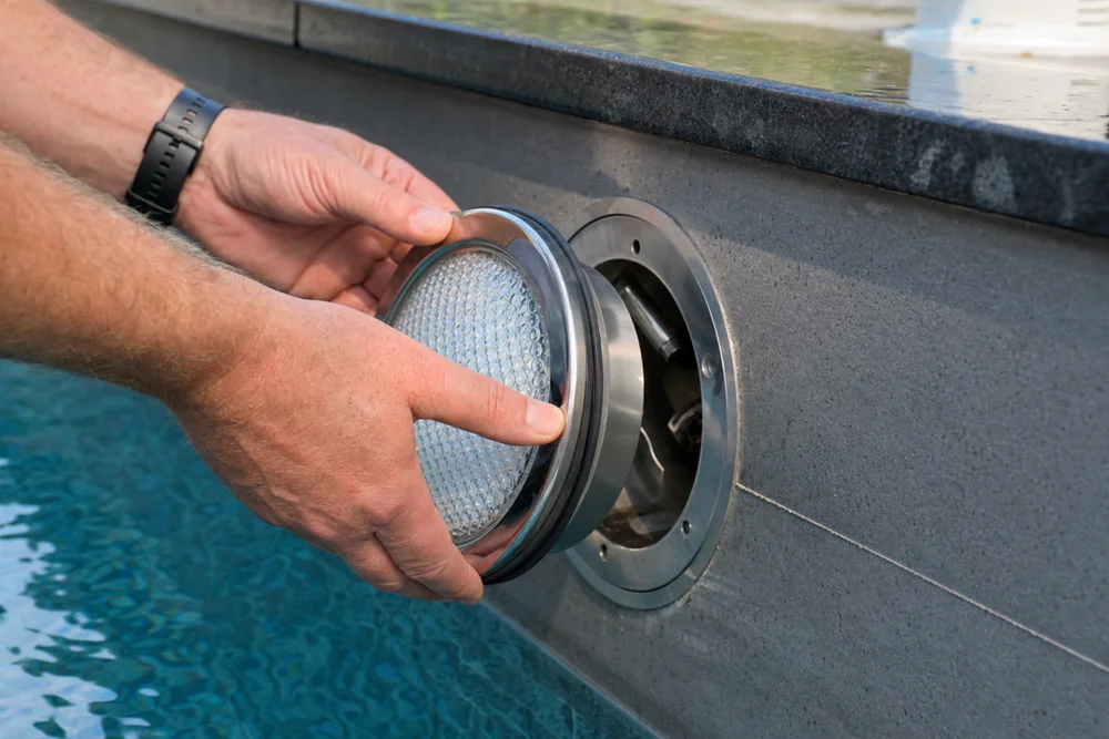 PAR56-LED-Leuchtmittel wird in die Scheinwerfernische am Pool eingesetzt PAR56-LED-Leuchtmittel wird in die Scheinwerfernische am Pool eingesetzt
