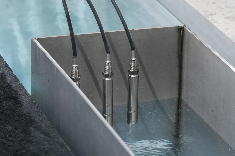 Tauchelektroden zur Niveauregelung hängen im Auffangbehälter eines Überlaufpools Tauchelektroden zur Niveauregelung hängen im Auffangbehälter eines Überlaufpools