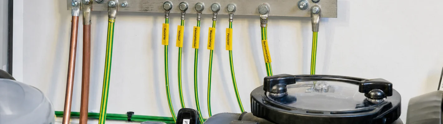 Potentialausgleichsschiene mit Kupferleiter an metallischen Pool-Einbauteilen im Technikraum