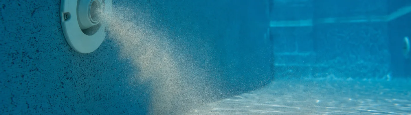 Feiner Sand rieselt aus einer Einlaufdüse auf den Boden eines Pools