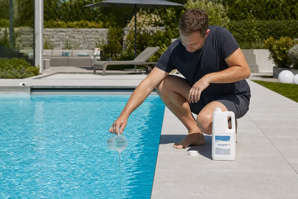 Dosierung eines Pool-Pflegemittels mit Messbecher am Beckenrand