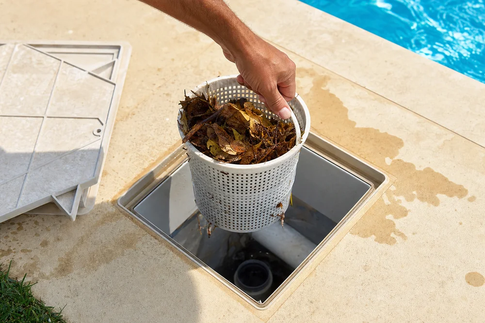 Hand entnimmt den vollen Vorfilterkorb aus einem Pool-Skimmer Hand entnimmt den vollen Vorfilterkorb aus einem Pool-Skimmer