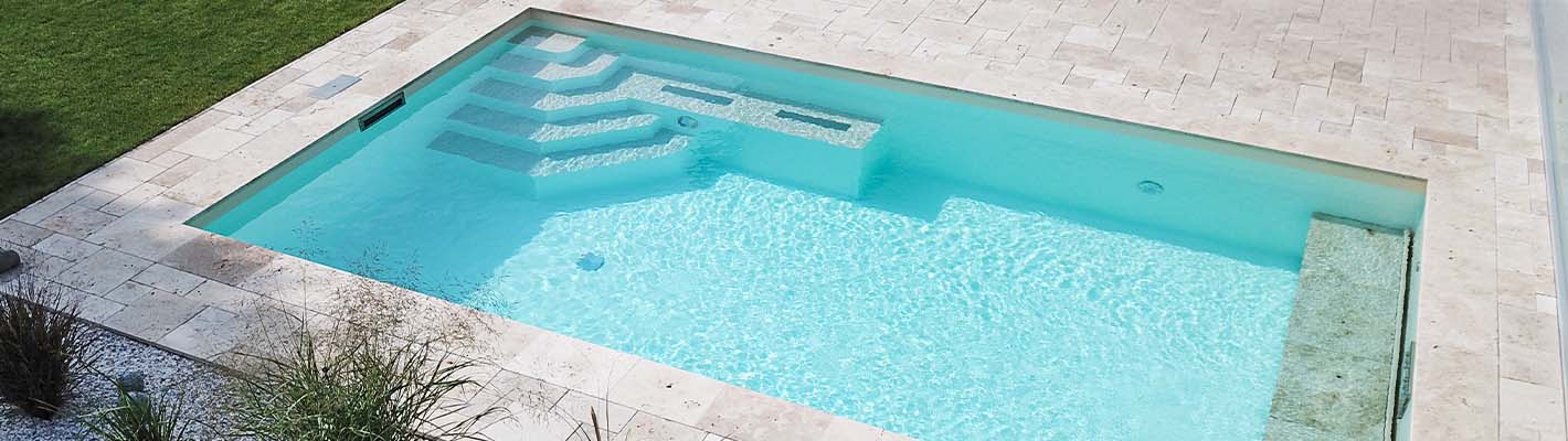 Verlegte Poolfolie in einem rechteckigen Betonpool mit integrierten Treppen und Sitzbank, eingefasst von hellen Travertinplatten und minimalistisch gestalteter Gartenumgebung.