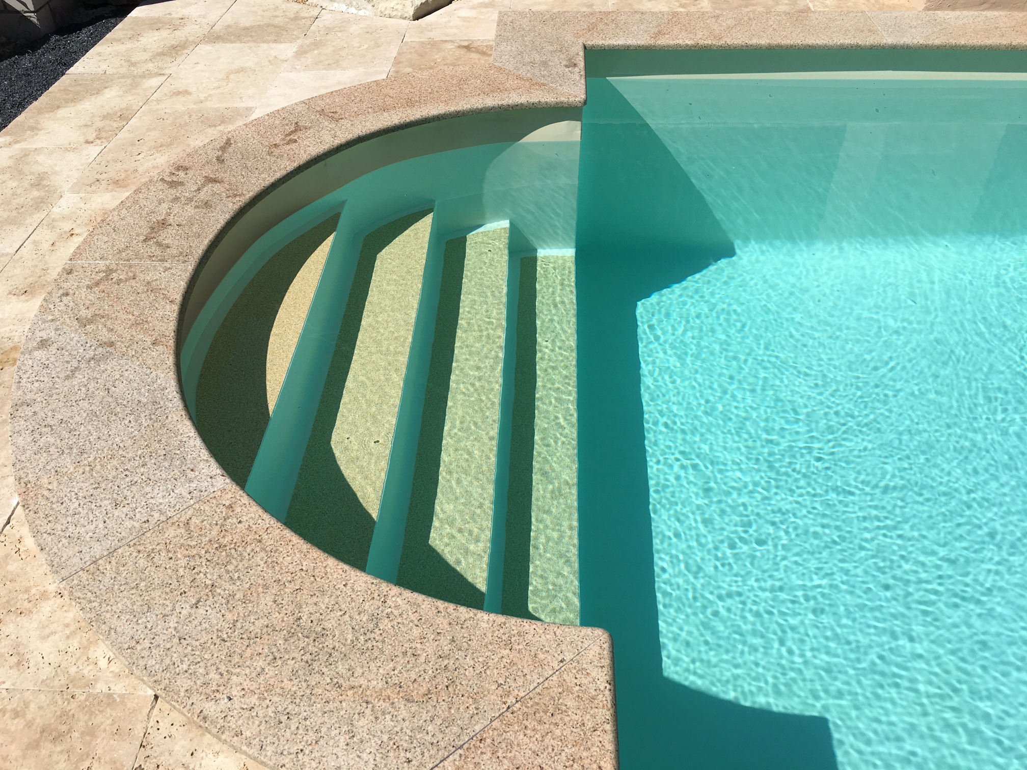 Detailansicht der römischen Treppe mit sandfarbener Folie und hellblauem Wasser im Schwimmbecken.