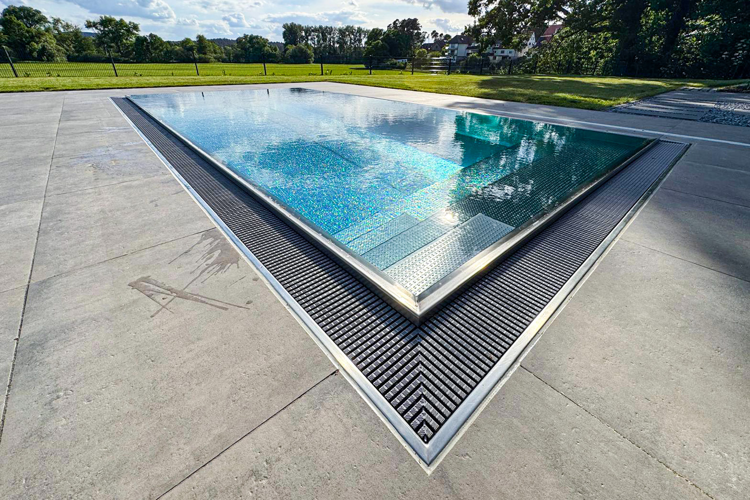Blick auf den Überlauf-Edelstahlpool mit genoppter Bodenfläche und Wasserlinie auf Beckenrandhöhe