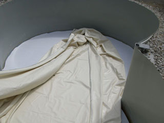 Beige Poolfolie wird in ein rundes Stahlwandbecken eingesetzt, der Boden ist mit Vlies ausgelegt.