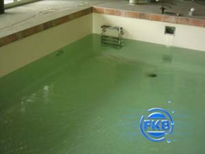 Hallenbad mit grünlicher Folieauskleidung, die teilweise mit Wasser gefüllt ist, von oben betrachtet.