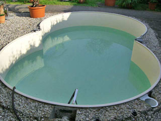 Achtform-Stahlwandbecken mit hellblauer Einhängefolie, teilweise mit Wasser gefüllt, umgeben von Kies.