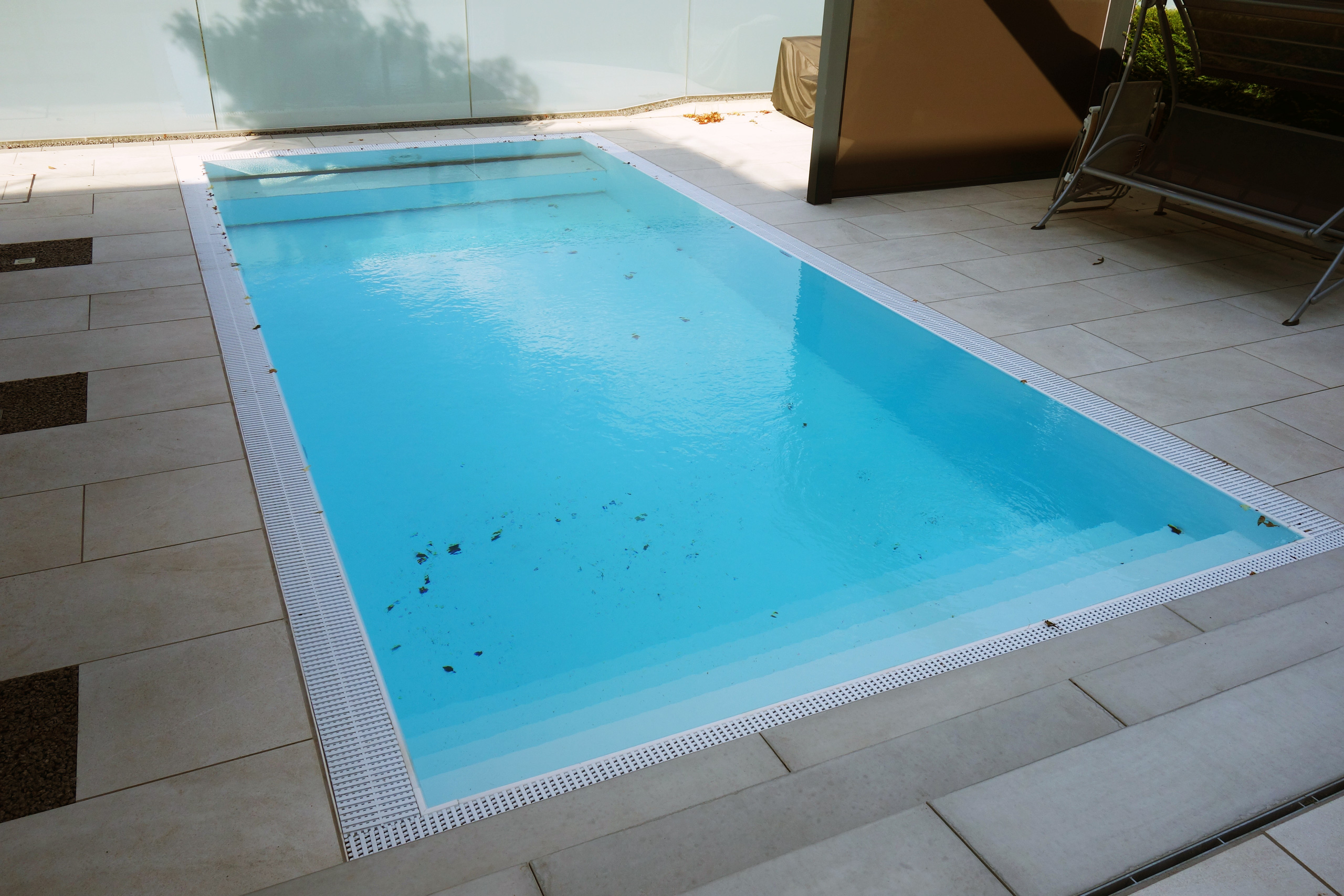 Detailansicht des Überlaufpools mit gerader Treppe, Podest und den weißen Überlaufrinnen.