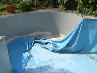 Alte, blaue Poolfolie wird aus einem Achtform-Stahlwandbecken entfernt, um eine Sanierung vorzubereiten.