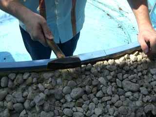 Einbau des Handlaufs am Stahlwandbecken mit Hammer und Gummiunterlage, im Hintergrund blaue Poolfolie