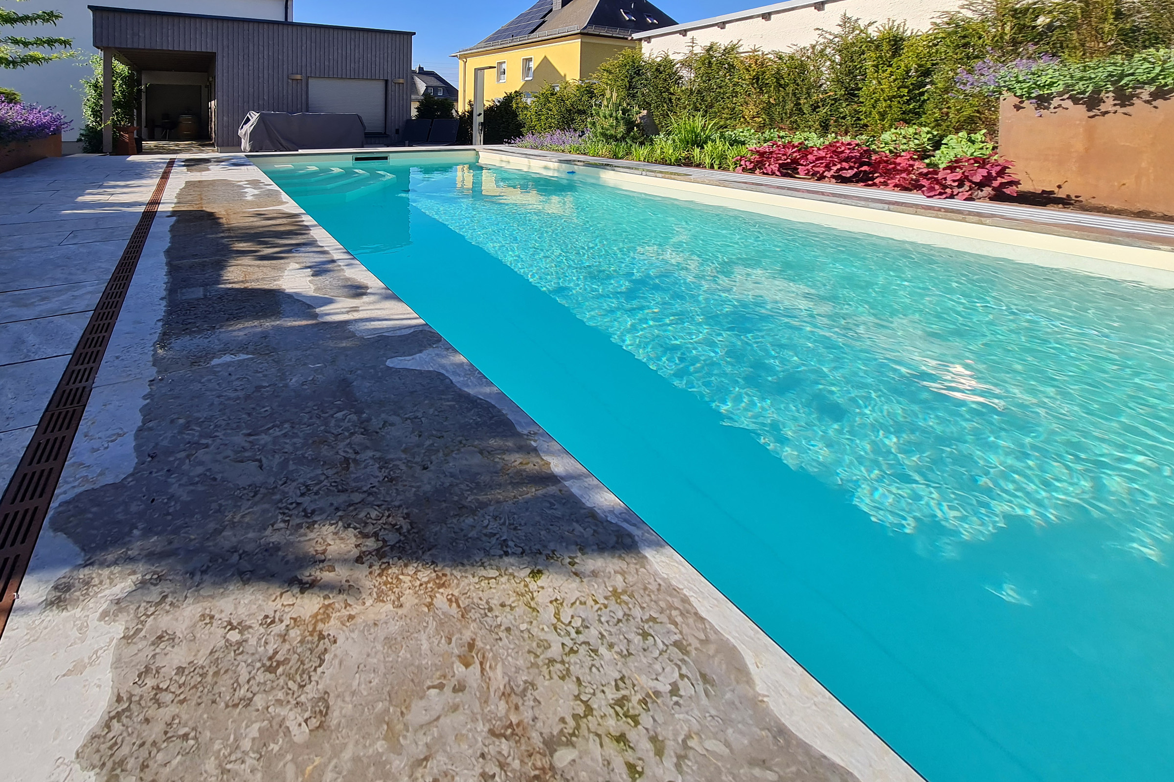 Pool in Gartenhanglage mit hochwertiger Randgestaltung aus Naturstein