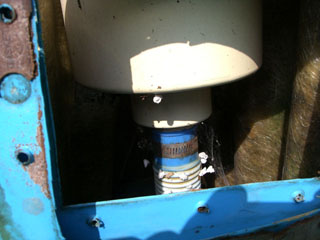 Detailansicht eines alten Skimmers mit blauer Stahlwand und verrosteten Schrauben, darunter ein verrohrtes Ablaufventil.