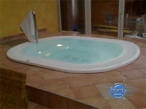 Ovaler Whirlpool-SPA MANDURA mit hellblauem Wasser und weißer Umrandung, Handtuchhalter im Hintergrund