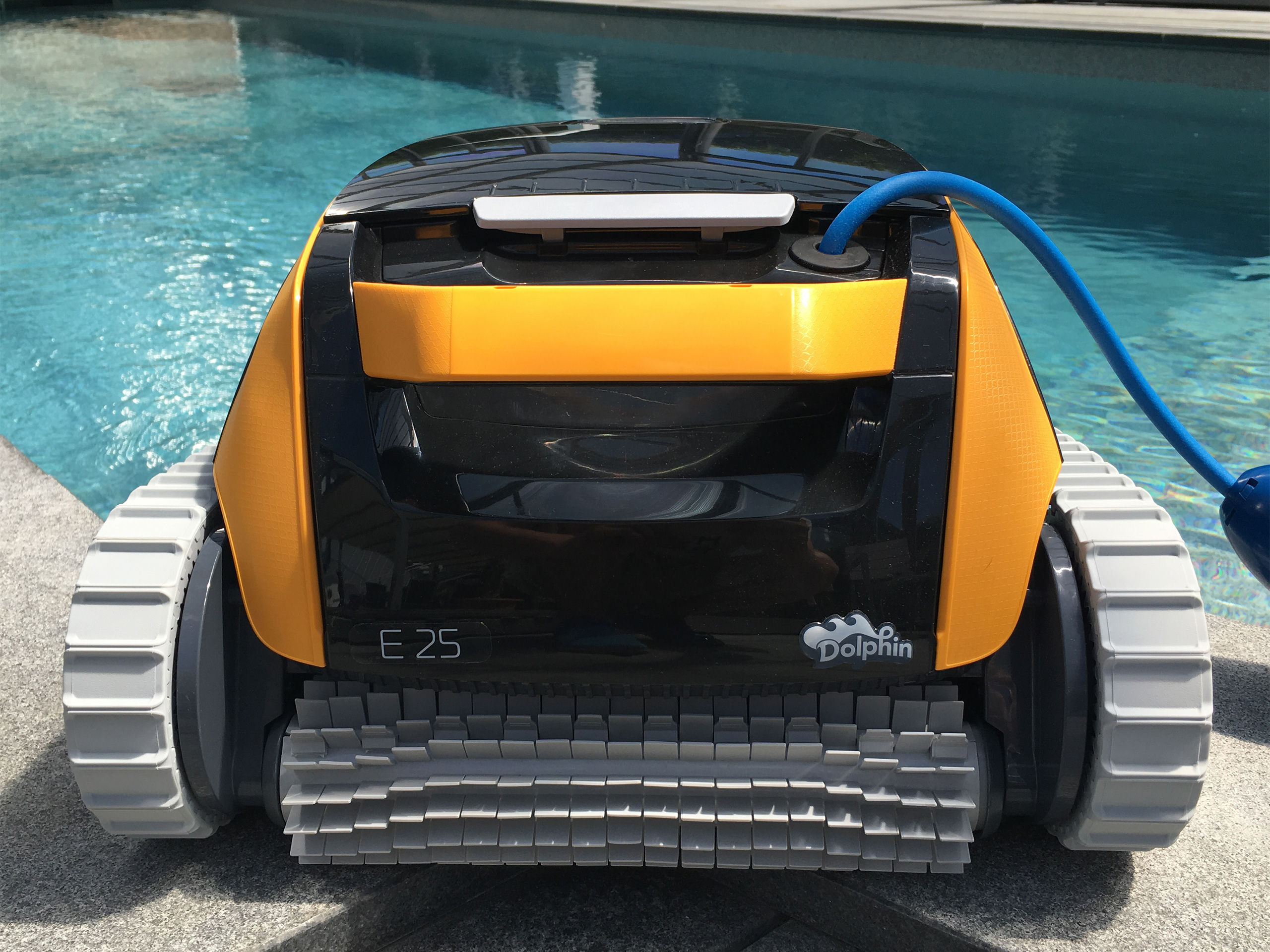 Dolphin E25 Poolsauger mit gelbem Gehäuse und blauer Zuleitung am Poolrand