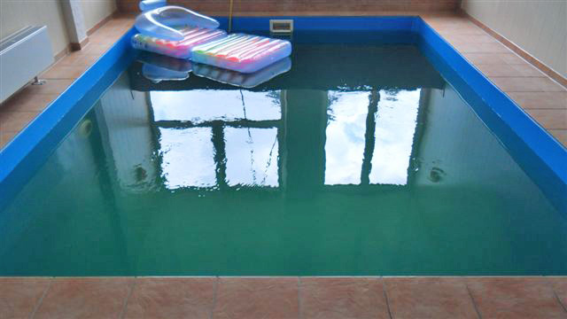 Hallenbecken mit blauer Einhängefolie und einem Luftbett auf der Wasseroberfläche