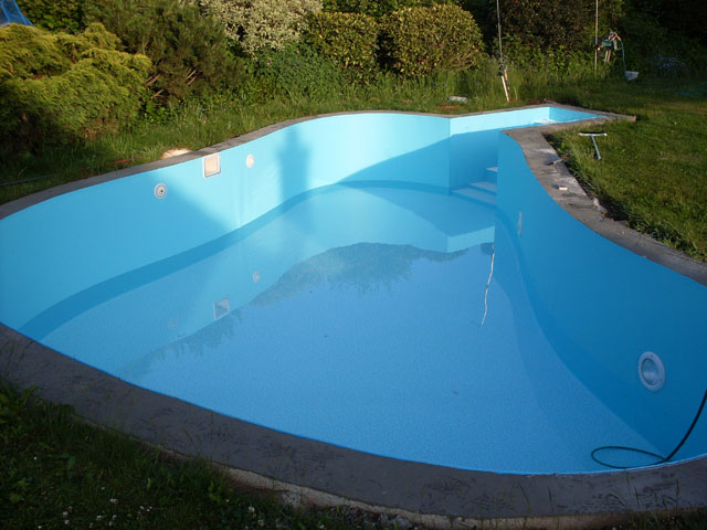 Freiformbecken mit blauer Folie, integrierter Treppe und Einbauteilen im Garten