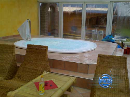 Eingebauter Whirlpool-SPA MANDURA mit Treppe und Handtuchhalter, umgeben von Rattan-Sesseln.