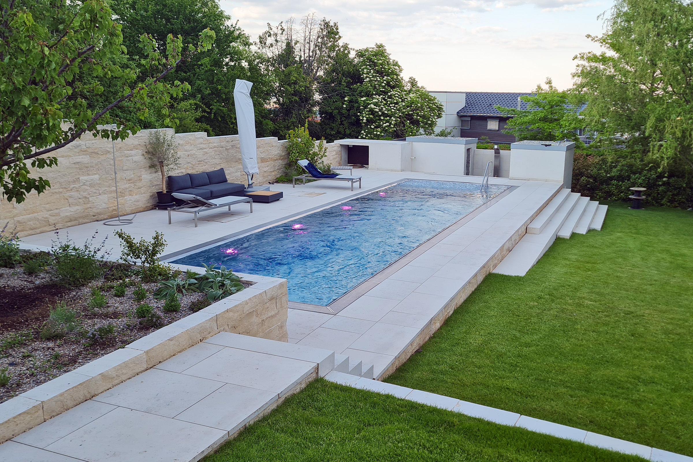 Edelstahlpool am Abend mit beleuchteter Wasserfläche