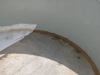 Detailansicht des Bodens eines Stahlwandbeckens mit sichtbaren Verschmutzungen und einer Folienrest-Ecke