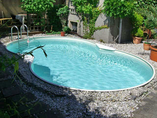 Achtform-Stahlwandbecken mit hellblauer Folie, umgeben von Kies und Pflanzen, im Garten eingebaut