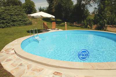 Runder Pool mit blauer Einhängefolie, Edelstahlleiter und Natursteinumrandung im Garten