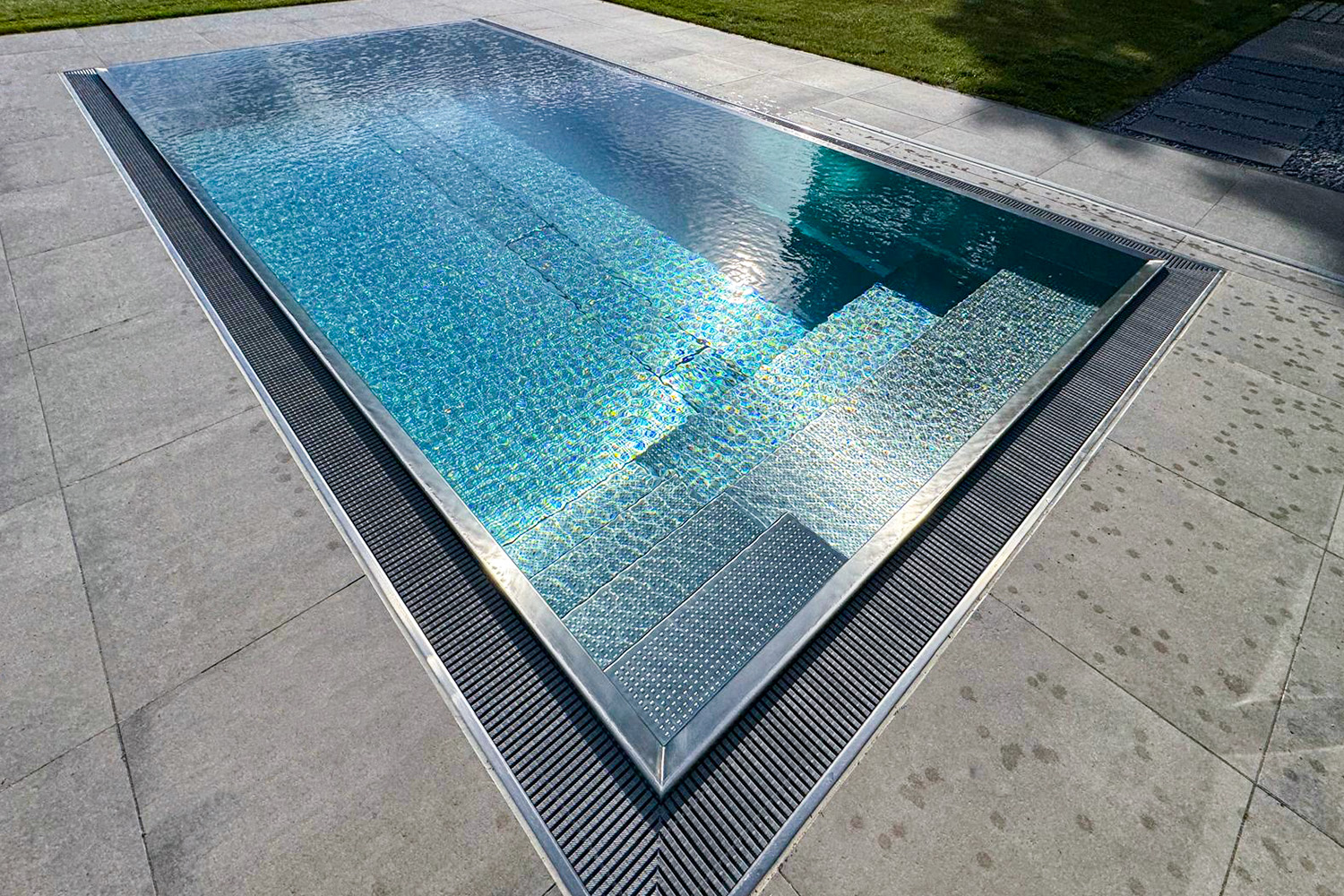 Frontalansicht des Edelstahlpools mit integrierter Sitzbank und glatter Wasserfläche