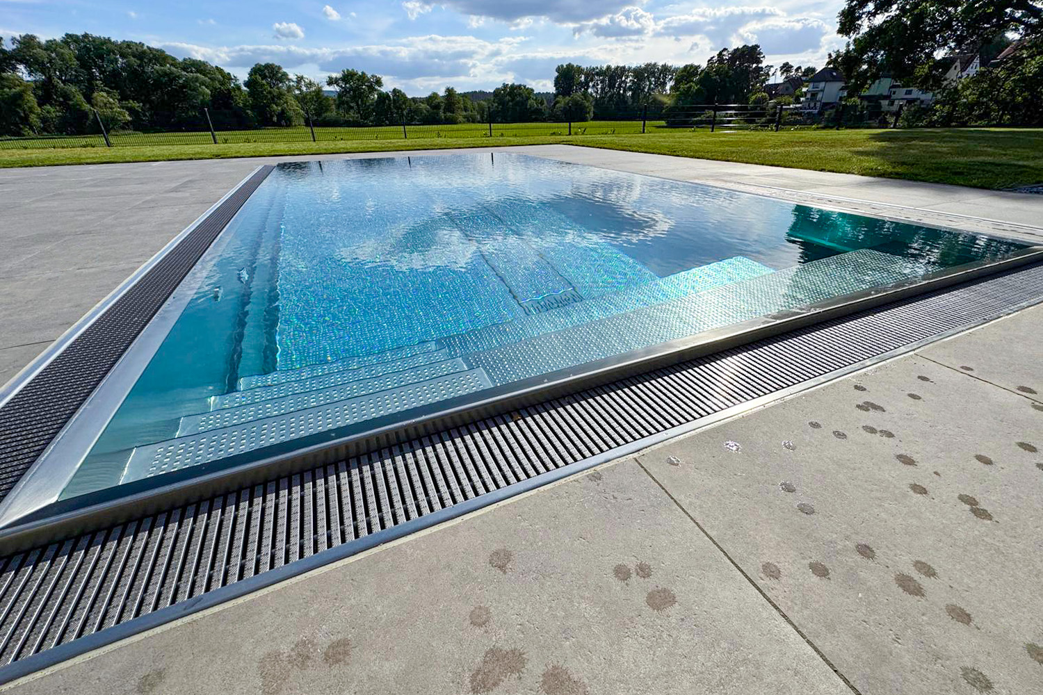 Edelstahlpool mit gerader Einstiegstreppe und umlaufender Rinne für Wasserüberlauf