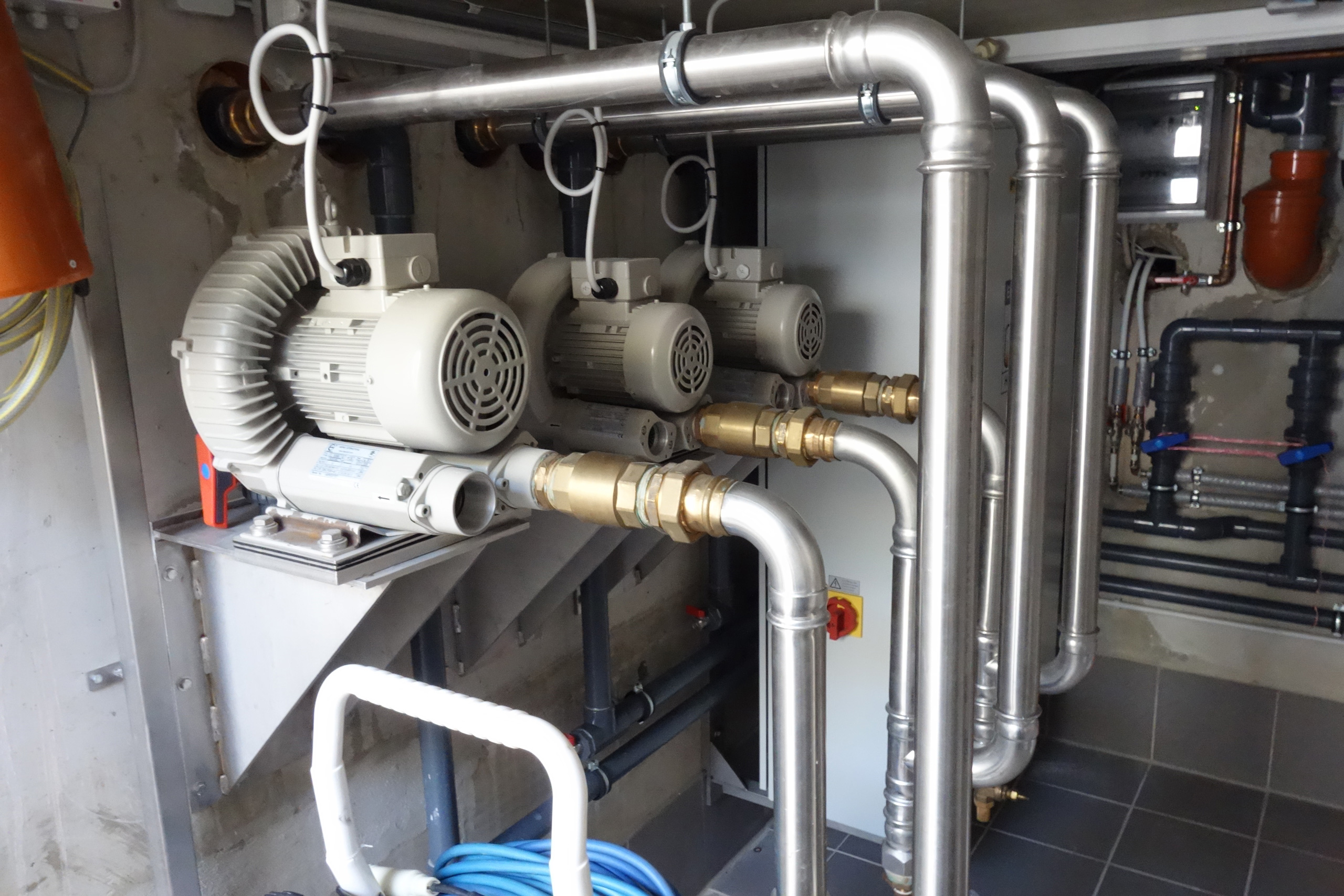 Detailansicht der Pooltechnik mit drei Gebläsen, Edelstahlrohren und Armaturen im Technikraum