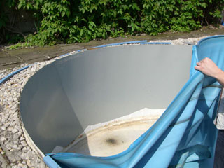 Alte Poolfolie wird aus einem Achtform-Stahlwandbecken entfernt, um eine Beckensanierung vorzubereiten.