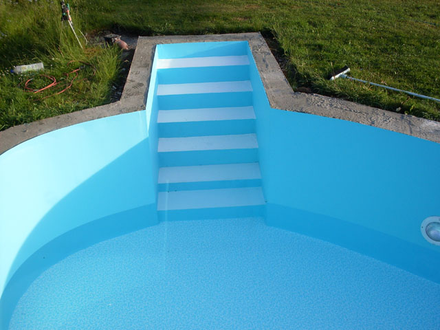 Freiformbecken mit blauer Folie und weißer Treppe, teilweise mit Wasser gefüllt