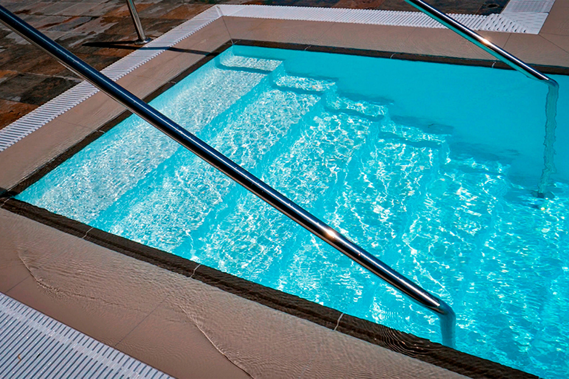 Schwimmbad mit hellblauer ELBE ELITE Schwimmbadfolie, integrierter Treppe und Edelstahlhandlauf